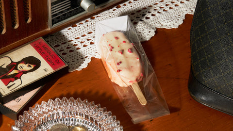 The same raspberry gelato bar, now part of a wider scene featuring vintage decor, including a classic radio, a book, and a crystal dish, evoking a nostalgic holiday atmosphere.