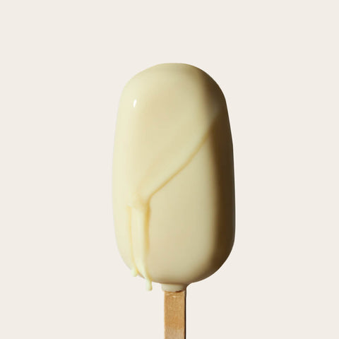 The Lemon Gelato Bar begins to melt slightly, showcasing the creamy yellow interior and glossy white shell, emphasizing its tangy and refreshing nature.