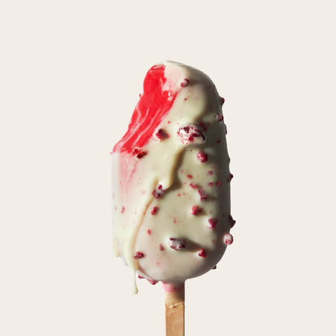 A Raspberry White Chocolate Gelato Bar with a bite taken out, revealing its rich, raspberry-flavoured gelato interior. The contrast between the creamy white chocolate shell and the vibrant gelato core creates a visually enticing treat against the light background.